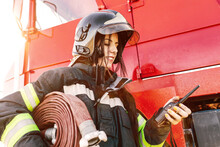Female Firefighter With Radio Near Fire Truck