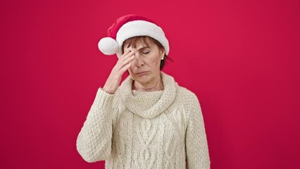 Sticker - Mature hispanic woman standing with tired expression wearing christmas hat over isolated red background