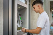 © Miljan Živković - man teenage student using credit card and withdraw cash at the ATM