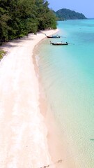 Wall Mural - Men and woman walking on the beach of Koh Kradan island in Thailand, a diverse couple of European men and Asian women on vacation in Thailand, drone aerial view from above