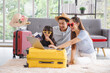 © aekkorn - Happy family tourist portrait. Father, mother and a daughter booking online air ticket, ready for travel with suitcase.