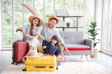 Wall Mural - Happy family tourist portrait. Father, mother and a daughter booking online air ticket, ready for travel with suitcase.