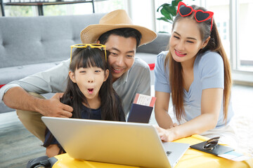 Wall Mural - Happy family tourist portrait. Father, mother and a daughter booking online air ticket, ready for travel with suitcase.