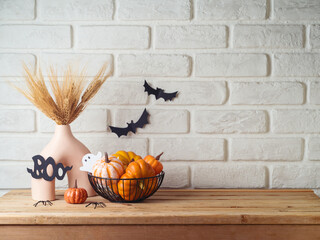 Wall Mural - Halloween background with modern vase and decoration on wooden table over brick wall. Empty space for product display