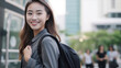 © JKLoma - Asian businesswoman go to work at office stand and smiling wear backpack on street around building on a city.
