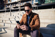 © baranq - Handsome man using mobile phone sitting on stairs in city