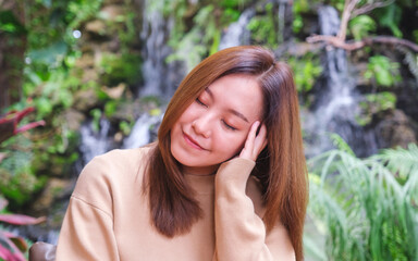 Wall Mural - Portrait image of a young woman with closed eyes sitting and relaxing in the garden