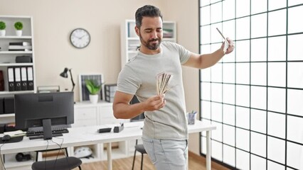 Poster - Young hispanic man business worker holding dollars dancing at office