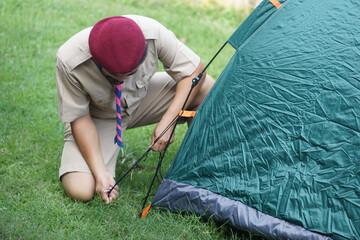 thai boy scout is setting up the tent at campsite for camping outdoor. concept, pitching camping ten