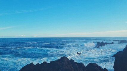 Wall Mural - Blue waves of the ocean crash against the rocks