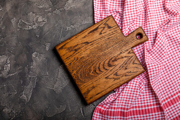 Wall Mural - Cutting board over towel on wooden kitchen table. Cutting board and kitchen towel on black textured background. Menu food card or recipes background concept.MOCKUP. Design. Place for text, copy space.