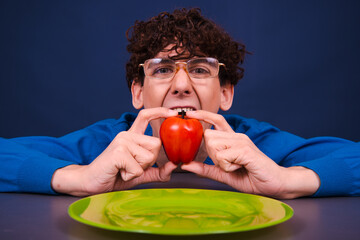 A young funny guy eats an apple. Vegetarianism and a healthy lifestyle.