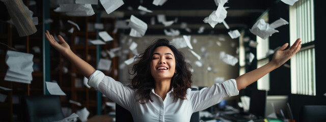 Happy businesswoman throwing papers in the air as a sign of victory and success in her work