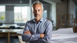 © Studio Nova - Male architect stands in an office in front of a desk with various architectural projects
