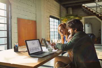 Wall Mural - Young colleagues going over paperwork design in a startup company office