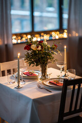 holidays, romantic date and celebration concept - close up of festive table serving for two with flowers in vase and candles burning at home on valentine's day