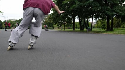 Wall Mural - Girl practicing roller scating in park riding outdoor with speed. Ptrtty teenager enjoying active summer leisure