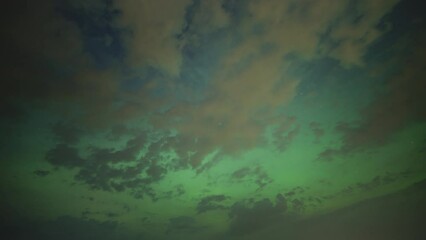 Wall Mural - The Northern Lights shining behind the clouds. Timelapse. 