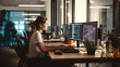 © IBEX.Media - Young woman sitting at desk in modern office with multiple computer displays typing on keyboard