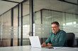 © insta_photos - Smiling busy older professional business man working on laptop sitting at desk. Older mature Indian businessman, happy male executive manager typing on computer using pc technology in office.