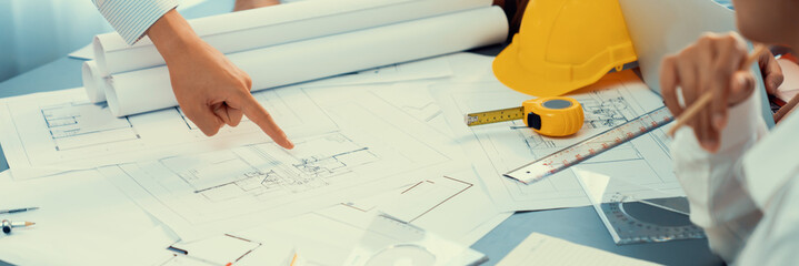 Engineer partner drawing and working on blueprint design together on office table for architectural building construction project. Architect drafting interior blueprint layout. Insight