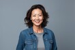 © Anne Schaum - Medium shot portrait photography of a Vietnamese woman in her 40s wearing a denim jacket against a minimalist or empty room background