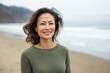 © Anne Schaum - Portrait photography of a Vietnamese woman in her 40s wearing a cozy sweater against a beach background