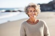 © Anne Schaum - Portrait photography of a French woman in her 60s wearing a cozy sweater against a beach background