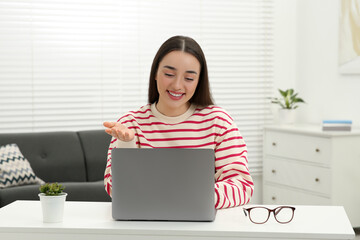 Canvas Print - Woman having video chat via laptop at white table indoors