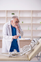 Wall Mural - Old male doctor and skeleton patient in the clinic