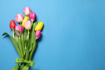 Wall Mural - Beautiful colorful tulip flowers and ribbon on light blue background, flat lay. Space for text