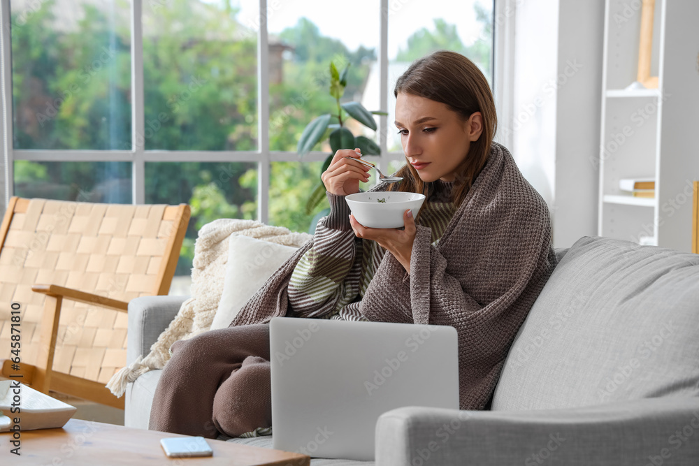 Ill young woman eating chicken soup at home