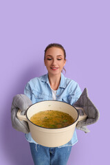 Wall Mural - Young woman with pot of chicken soup on lilac background