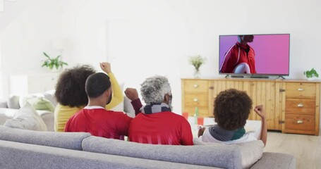 Canvas Print - Biracial family watching tv with african american male rugby player with ball on screen