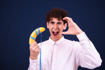 Funny curly guy eating a banana and posing on a blue background.