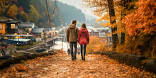 Rear View Of A Couple In Love Holding Hands And Walking Away In The Golden Yellow Autumn Countryside Near A Lake