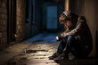 Sad teenager sitting in an alleyway all alone at night. Depressed helpless man sitting in the dark alleyway, feeling sadness and pain