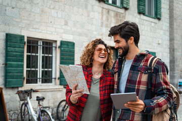 Lovely couple traveling with a map and digital tablet in the city. Two digital nomads exploring a new  Mediterranean town they've just settled in.