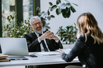 Canvas Print - Happy mature man in formalwear interviewing job candidate while sitting at the desk in office