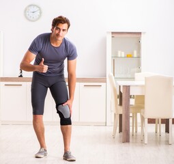 Wall Mural - Young man with injured knee recovering at home