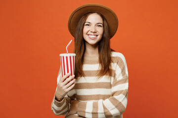 Sticker - Young woman she wear striped sweater hat casual clothes hold in hand cup of soda pop cola fizzy water look camera isolated on plain orange red color wall background studio portrait. Lifestyle concept.