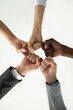 © fizkes - Close up view from below of multiethnic businesspeople give fists bump show team unity and support at work, diverse colleagues join hands engaged in teambuilding activity together, teamwork concept