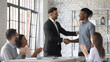 © fizkes - Smiling Caucasian businessman shake hand congratulate with good work achievement result african American male employee, boss handshake greeting with promotion excited biracial worker at meeting