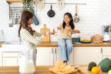 Portrait of enjoy happy love asian family mother with little asian girl smiling and having protein breakfast drinking and hold glasses of milk on counter in kitchen at home.Diet concept.healthy drink