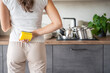 © dtatiana - Back view of young woman holding sponge for washing dishes and upcoming cleaning her house
