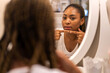 © Art_Photo - Smiling of african american woman clean healthy skin looking at mirror.beauty and fashion,hair,black skin,skin care,cosmetics,cosmetology,african girl apply cream moisturizer on face.spa and wellness