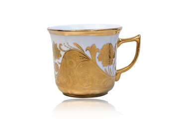 Antique porcelain coffee cup on white background with reflection. Dishes with gold pattern. Table service.