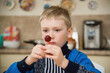 © Dmitry - blond boy is sitting at the kitchen table holding a candy Lollipop in his hands. thoughtful serious look