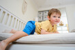 © Андрей Журавлев - The baby is in danger of falling down while playing on the bed. Kid aged two years (two-year-old boy)