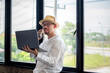 © Wasana - Businessman in casual clothes leaning against the glass window working using laptop and making a phone call.